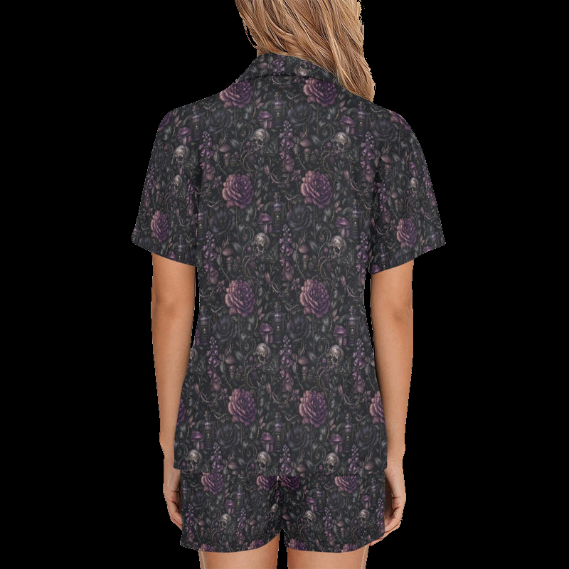 Back view of woman wearing black night floral short pajamas with purple skull-and-flower print on a black background