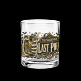 Skeleton hand gripping the glass beside an ornate Last Pour label on whiskey glasses