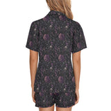Back view of woman wearing black night floral short pajamas with purple skull-and-flower print