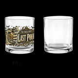 Skeleton hand gripping the glass beside an ornate Last Pour label on whiskey glasses, product view 2